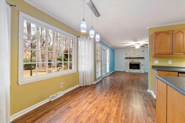 unfurnished living room with crown molding, a fireplace, dark hardwood / wood-style floors, and ceiling fan