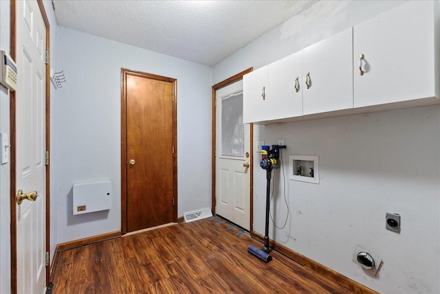 clothes washing area featuring cabinets, a textured ceiling, dark hardwood / wood-style flooring, hookup for a washing machine, and electric dryer hookup