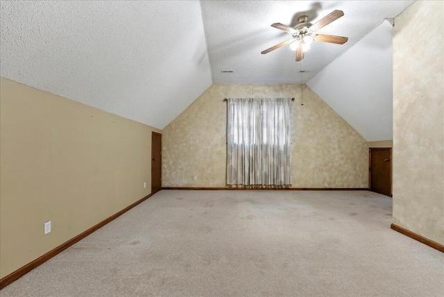 additional living space featuring ceiling fan, vaulted ceiling, light carpet, and a textured ceiling