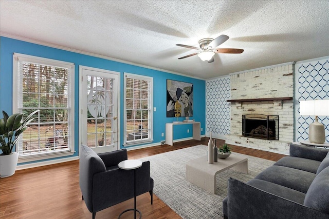 living room with crown molding, a brick fireplace, hardwood / wood-style floors, and a textured ceiling