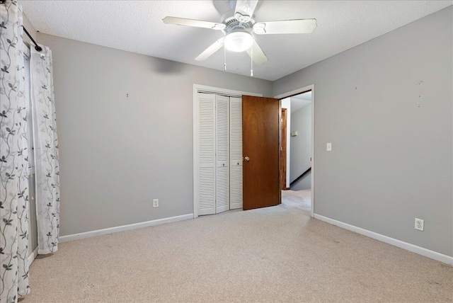 unfurnished bedroom with light colored carpet, a textured ceiling, ceiling fan, and a closet