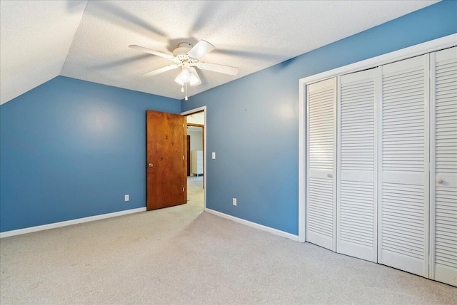 unfurnished bedroom featuring lofted ceiling, light colored carpet, ceiling fan, and a closet