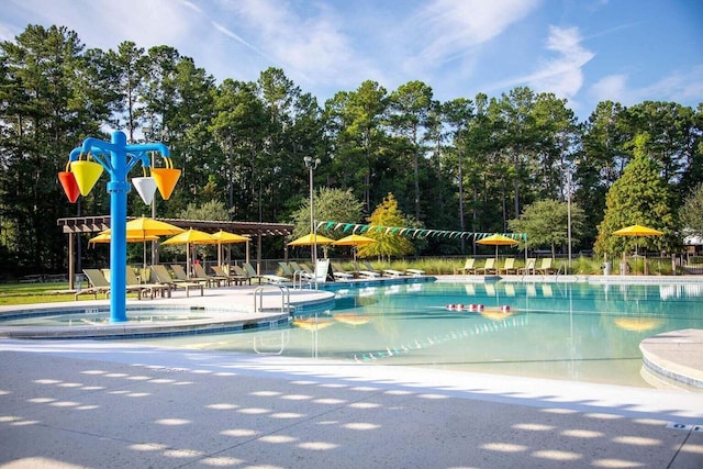 community pool with a patio and view of wooded area
