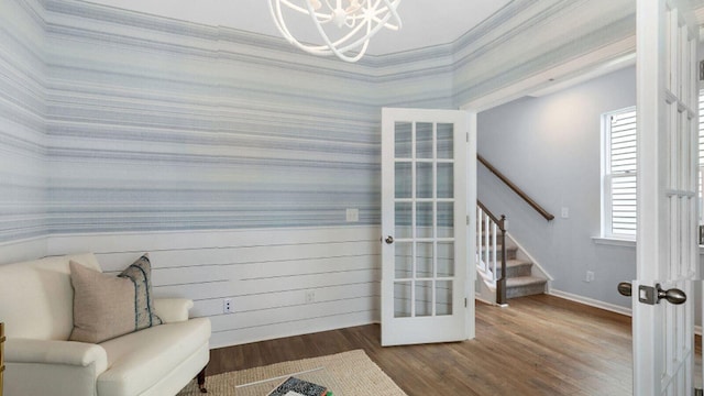 living area featuring wallpapered walls, a chandelier, stairway, wood finished floors, and french doors