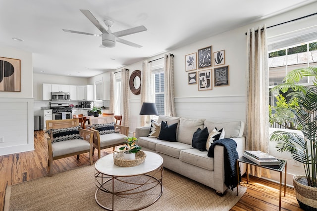170 Spring St, Charleston, SC 29403 - living room with light wood-style floors, a ceiling fan, and a wainscoted wall