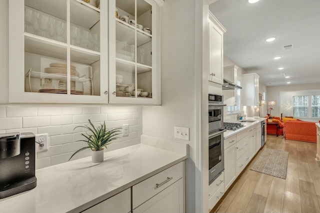 kitchen featuring white cabinetry, decorative backsplash, stainless steel gas cooktop, and light wood-type flooring