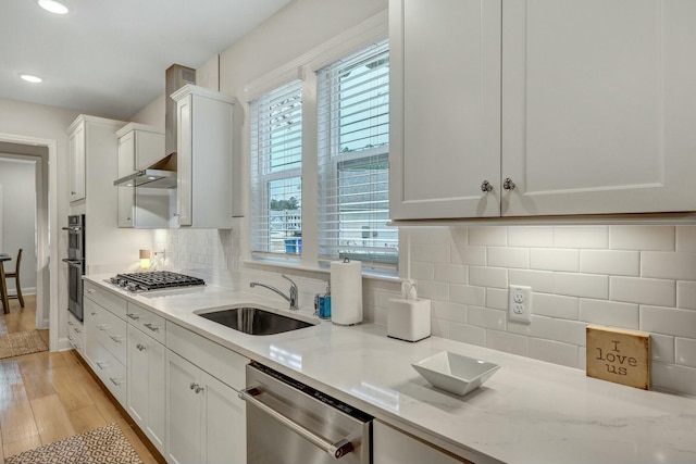 kitchen with appliances with stainless steel finishes, tasteful backsplash, sink, white cabinets, and light stone countertops