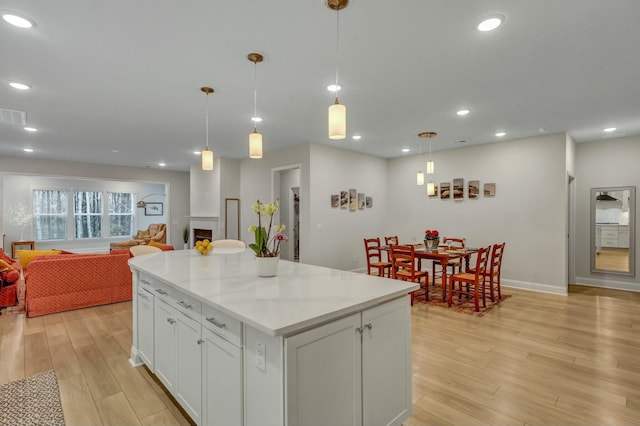 kitchen featuring pendant lighting, white cabinetry, light hardwood / wood-style floors, and a kitchen island