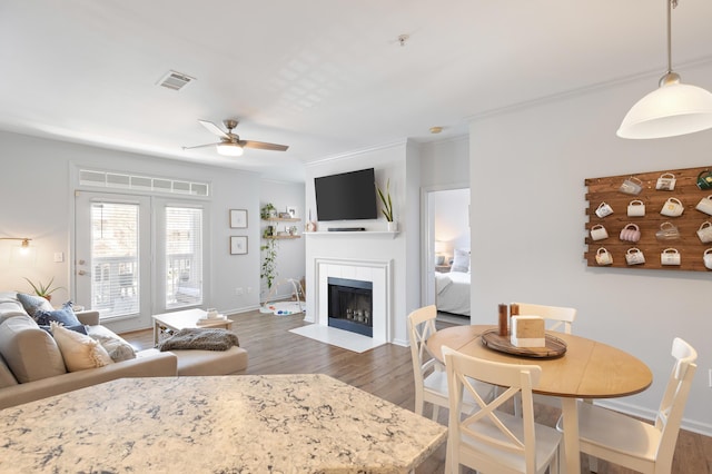 living room with a tile fireplace, ornamental molding, dark wood-type flooring, and ceiling fan