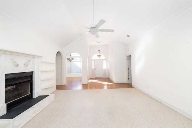 unfurnished living room featuring hardwood / wood-style floors, lofted ceiling, ceiling fan, ornamental molding, and a premium fireplace