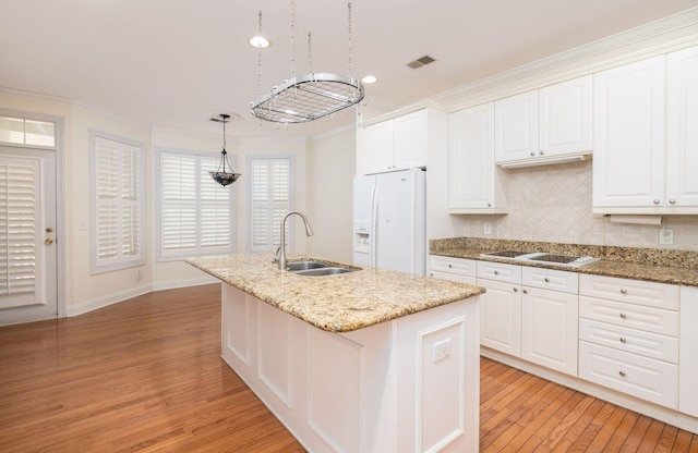 kitchen featuring white appliances, sink, decorative light fixtures, a center island with sink, and light hardwood / wood-style floors