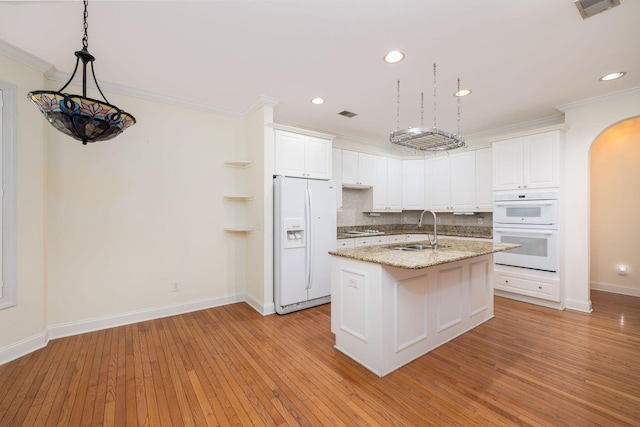 kitchen featuring white cabinetry, sink, an island with sink, light hardwood / wood-style floors, and white appliances