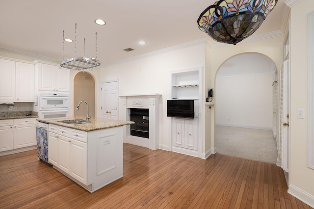 kitchen with white cabinetry, sink, a kitchen island with sink, and light hardwood / wood-style flooring