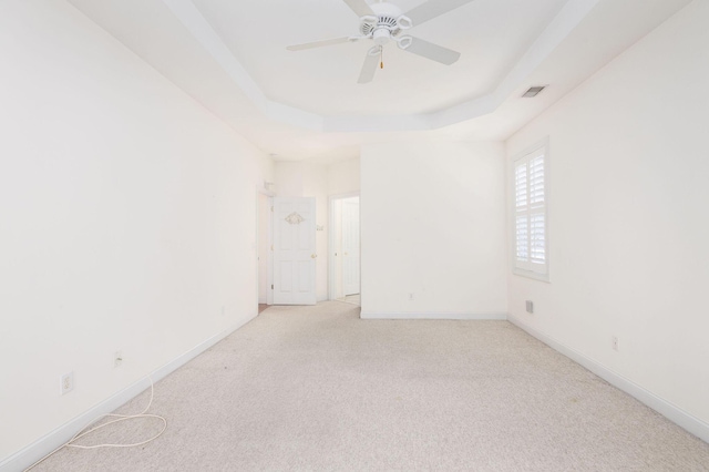 carpeted empty room with ceiling fan and a tray ceiling