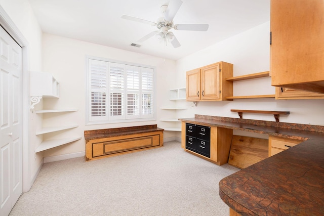 kitchen featuring light carpet, light brown cabinets, built in desk, and ceiling fan