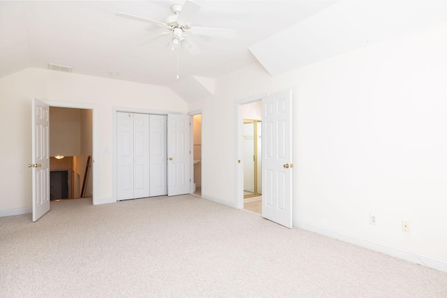 unfurnished bedroom featuring ceiling fan, light colored carpet, lofted ceiling, and a closet