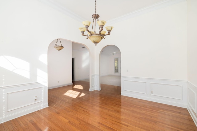 unfurnished room with hardwood / wood-style floors, ceiling fan with notable chandelier, and ornamental molding