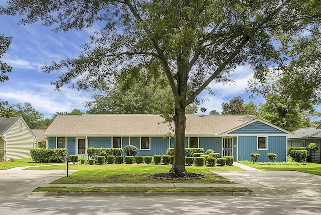 ranch-style home featuring concrete driveway and a front lawn