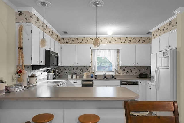 kitchen featuring white appliances, a kitchen breakfast bar, hanging light fixtures, a peninsula, and white cabinetry