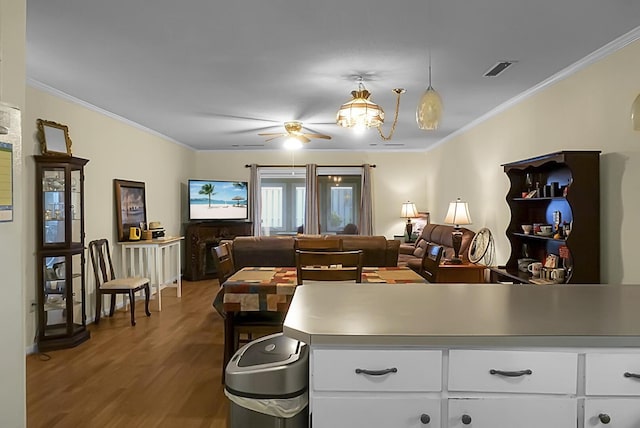 living room featuring ornamental molding, visible vents, ceiling fan, and wood finished floors