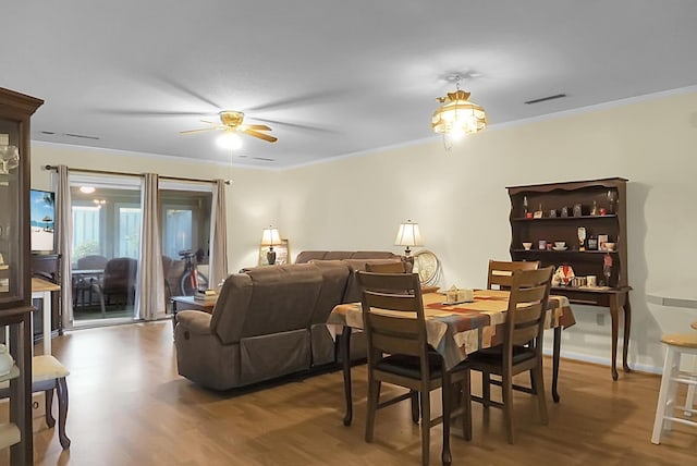 dining area with visible vents, ornamental molding, a ceiling fan, wood finished floors, and baseboards