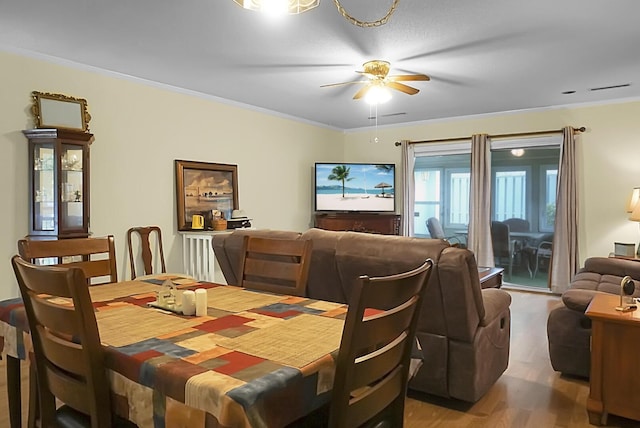 dining space featuring a ceiling fan, crown molding, and wood finished floors