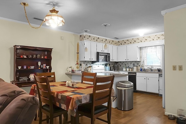 kitchen with white cabinets, ornamental molding, a peninsula, black microwave, and range with electric stovetop