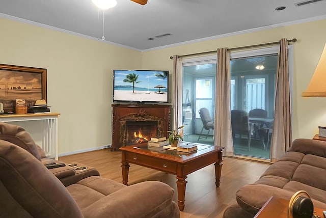 living area featuring light wood-style floors, a fireplace, baseboards, and crown molding