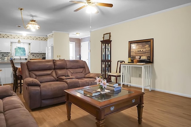 living area featuring light wood-style floors, plenty of natural light, ornamental molding, and baseboards