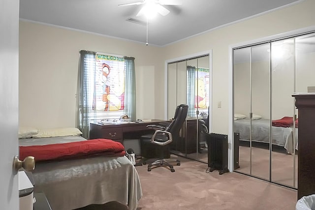 bedroom with ceiling fan, light carpet, visible vents, two closets, and crown molding