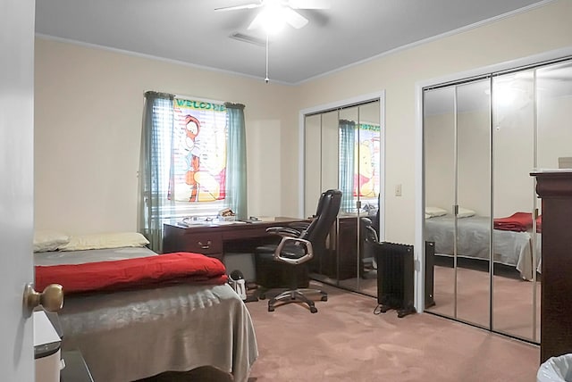 bedroom with two closets, crown molding, ceiling fan, and carpet flooring