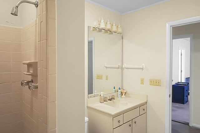 bathroom featuring toilet, tiled shower, vanity, and crown molding