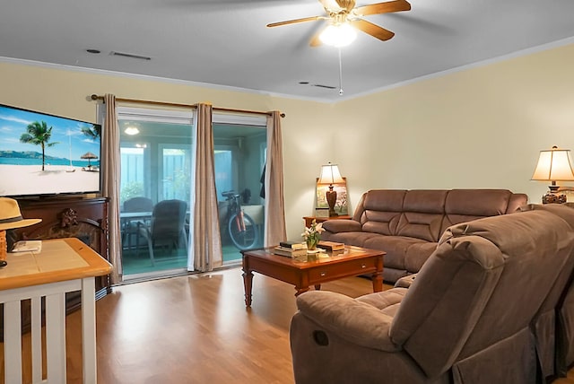 living room with wood-type flooring, ornamental molding, and ceiling fan