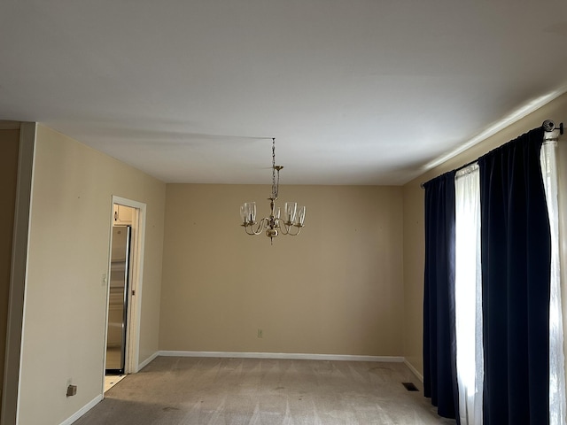 spare room with baseboards, light colored carpet, an inviting chandelier, and visible vents