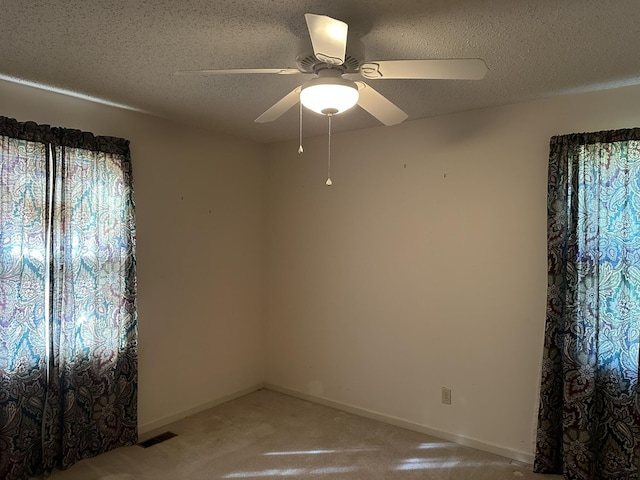 spare room with visible vents, a ceiling fan, a textured ceiling, and light colored carpet