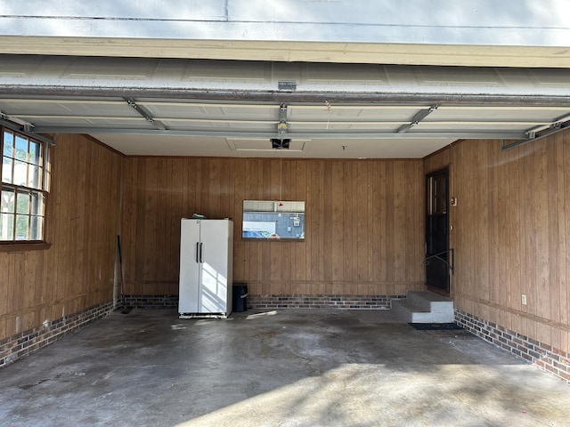 garage featuring freestanding refrigerator and wood walls