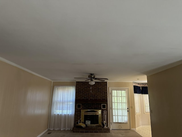 unfurnished living room featuring crown molding, baseboards, a ceiling fan, and a brick fireplace