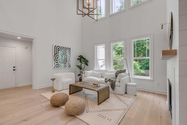 7053 Schooner St, Daniel Island, SC 29492 - living area featuring a high ceiling, light wood-style flooring, baseboards, a chandelier, and a fireplace