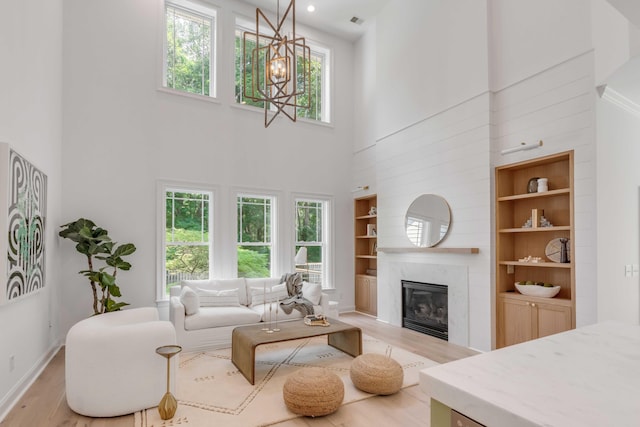 7053 Schooner St, Daniel Island, SC 29492 - living area featuring built in features, light wood finished floors, a high ceiling, a glass covered fireplace, and baseboards
