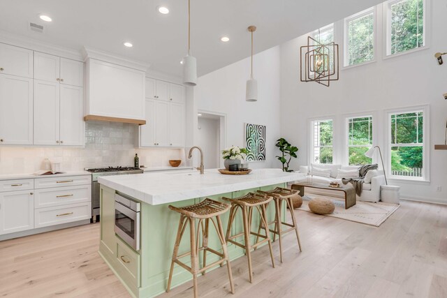 7053 Schooner St, Daniel Island, SC 29492 - kitchen with stainless steel appliances, white cabinetry, a kitchen breakfast bar, light wood-style floors, and recessed lighting