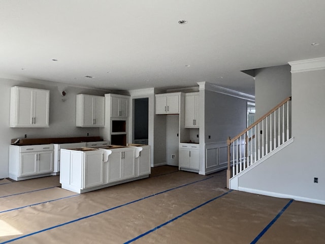 kitchen featuring recessed lighting, white cabinetry, crown molding, and baseboards