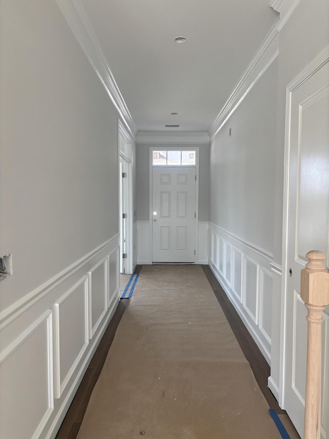 interior space with a wainscoted wall, ornamental molding, and a decorative wall