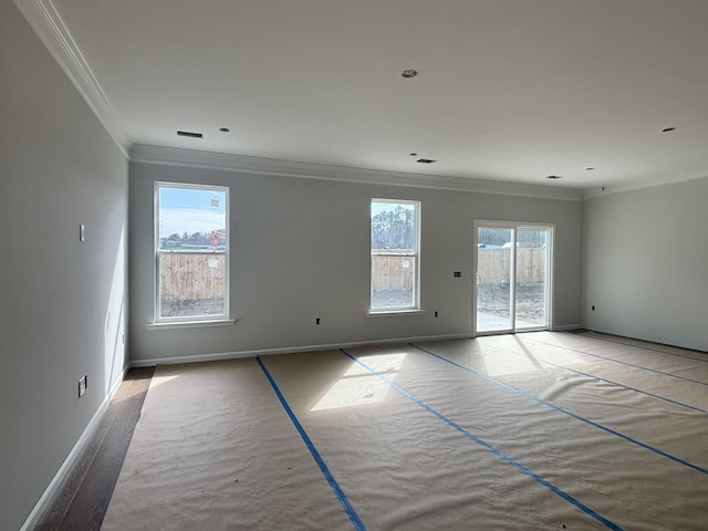 spare room with visible vents, baseboards, and crown molding