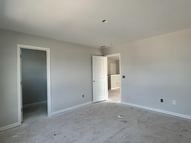 unfurnished bedroom with a spacious closet and baseboards