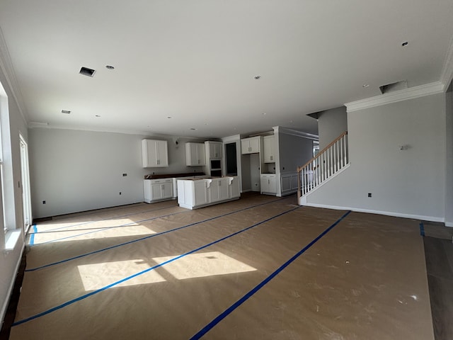 unfurnished living room with baseboards, stairway, and crown molding