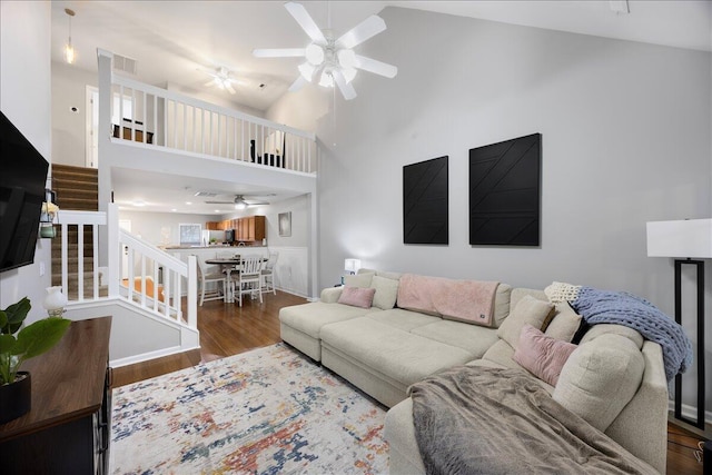 living area with stairway, wood finished floors, high vaulted ceiling, and ceiling fan