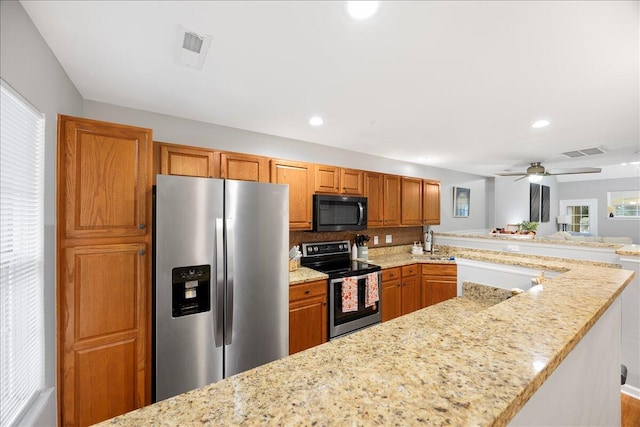 kitchen featuring stainless steel appliances, light stone countertops, visible vents, and brown cabinetry