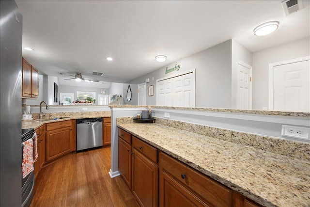 kitchen with brown cabinetry, visible vents, dark wood-style flooring, a sink, and appliances with stainless steel finishes