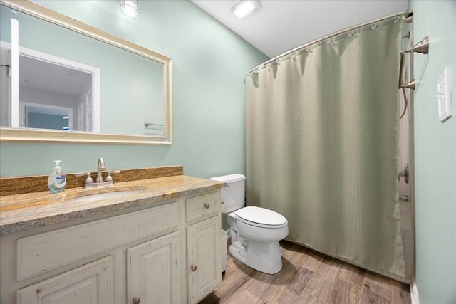 full bathroom featuring vanity, a shower with shower curtain, toilet, and wood finished floors