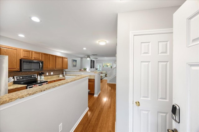 kitchen featuring light wood-type flooring, electric range, brown cabinets, recessed lighting, and decorative backsplash